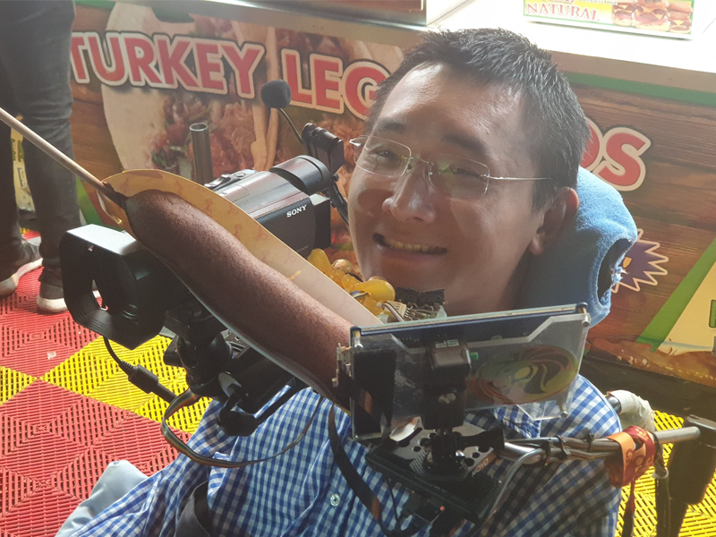 Paul at the LA County Fair, holding a giant corn dog that is the size longer than his head.